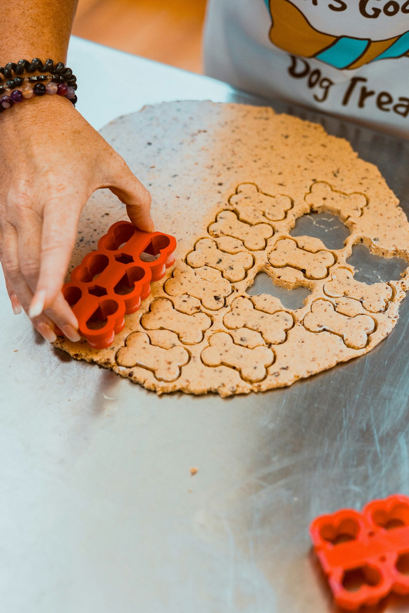 Bone-shaped dog treats being cut from dough